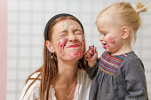 Mom and baby playing with face paint, family time concept