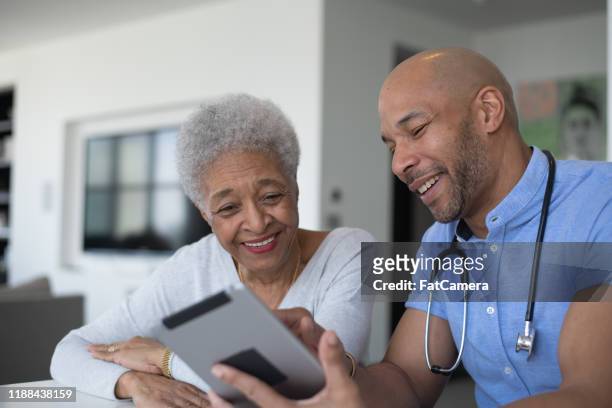mixed race male doctor consulting avec une photo de stock de patient âgé - medicare photos et images de collection