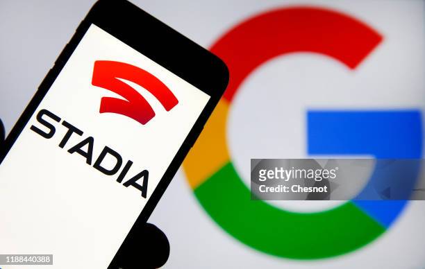 In this photo illustration, the Stadia logo is displayed on the screen of an iPhone in front of a computer screen displaying the Google logo on...