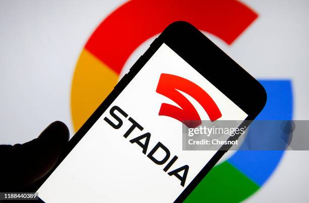 In this photo illustration, the Stadia logo is displayed on the screen of an iPhone in front of a computer screen displaying the Google logo on...