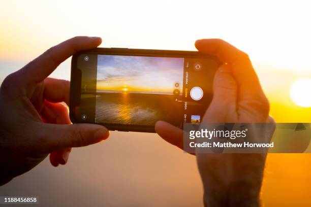 Man photographs a sunset with an Apple iPhone 11 Pro at Southerndown on November 18, 2019 in Bridgend, United Kingdom.