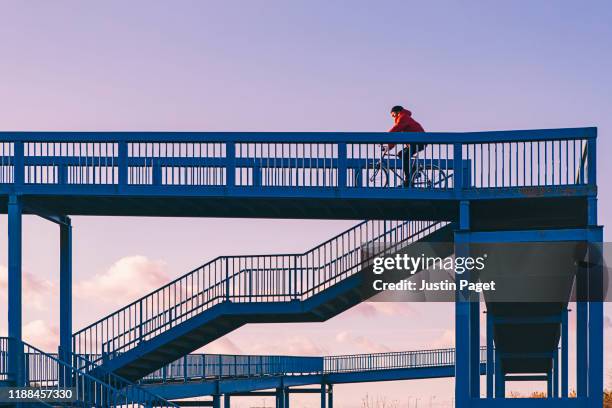man cycling over pedestrian bridge - elevated walkway stock pictures, royalty-free photos & images