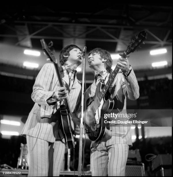 English Rock and Pop musicians Paul McCartney , on bass, and John Lennon , on guitar, both of the group the Beatles, as they perform onstage at...