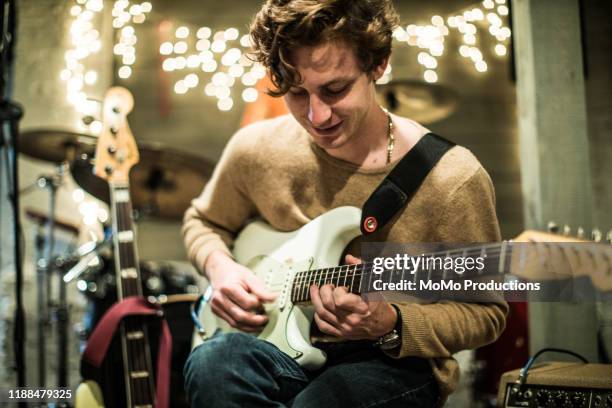 young man playing electric guitar at band rehearsal - elektrogitarre stock-fotos und bilder