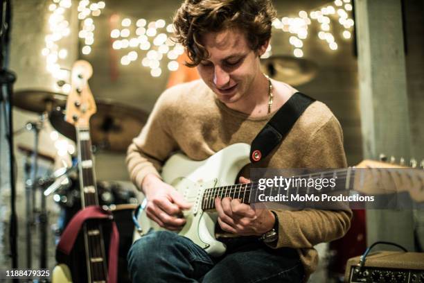 young man playing electric guitar at band rehearsal - man playing guitar photos et images de collection