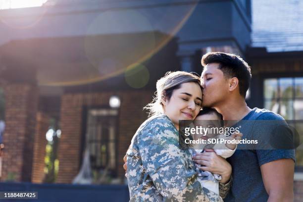 mid adult man kisses his soldier wife - armed forces stock pictures, royalty-free photos & images