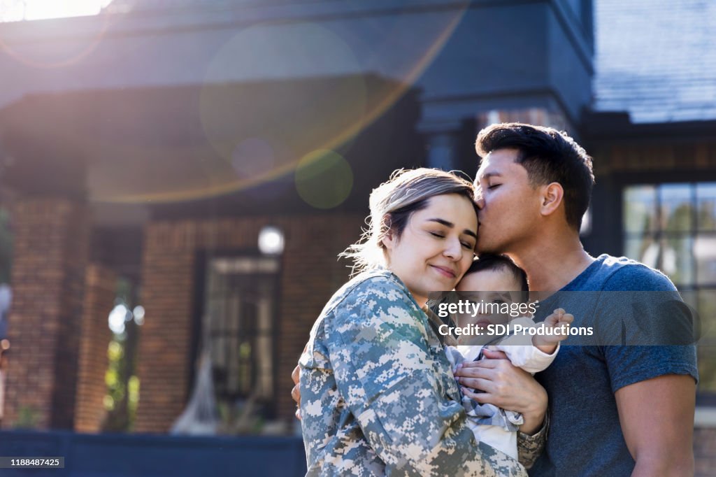 O homem adulto meados de beija sua esposa do soldado