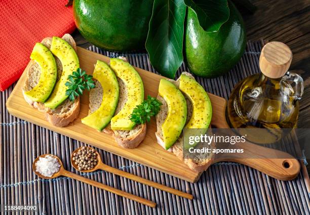 snack or appetizer of avocado slices bruschetta with olive oil, peppermint and salt - aguacates stock pictures, royalty-free photos & images