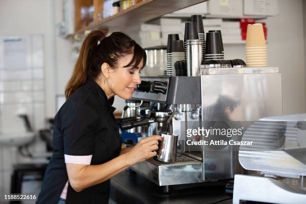 female barista checking milk in coffee shop - melbourne cafe stock-fotos und bilder