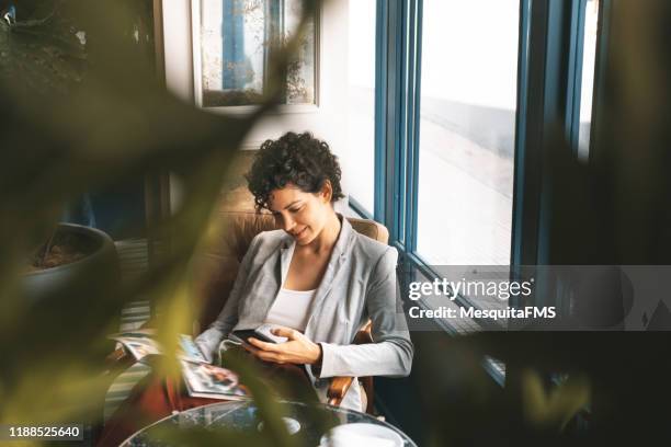 geschäftsfrau entspannt sich in der hotellobby - frau zeitschrift liest stock-fotos und bilder