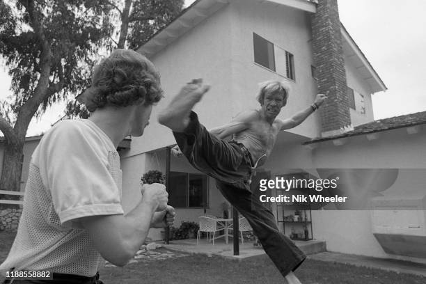 Action hero movie star Chuck Norris practices kung fu style moves with a trainer in back yard of his house in Palos Verdes circa 1978