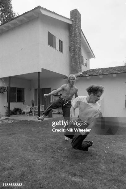 Action hero movie star Chuck Norris practices kung fu style moves with a trainer in back yard of his house in Palos Verdes circa 1978