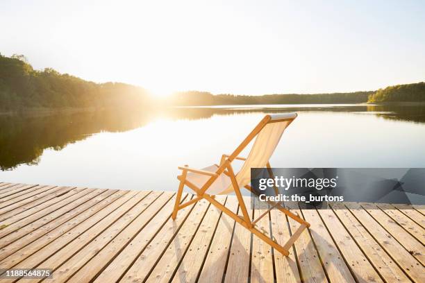 deck chair on jetty at an idyllic lake during sunset - デッキチェア ストックフォトと画像