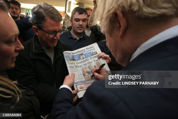 Britain's Prime Minister Boris Johnson signs a copy of The Northern Echo for a supporter during a visit to see newly elected Conservative party MP...