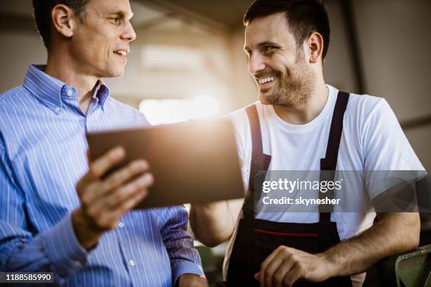 happy manager and manual worker talking while using touchpad in a workshop. - repairman stock pictures, royalty-free photos & images