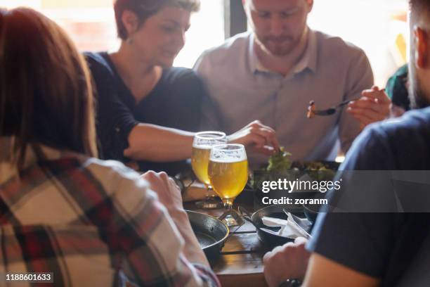 picking lettuce from friend's plate at the table in a pub - gastro pub stock pictures, royalty-free photos & images