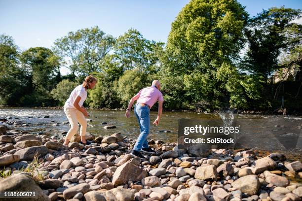 älteres paar springt steine - skimming stones stock-fotos und bilder