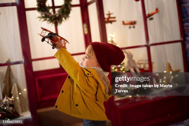 boy making a plane fly in front of a christmas toy store - loja de brinquedos imagens e fotografias de stock