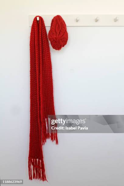 red scarf and hat hanging on rack - schal freisteller stock-fotos und bilder