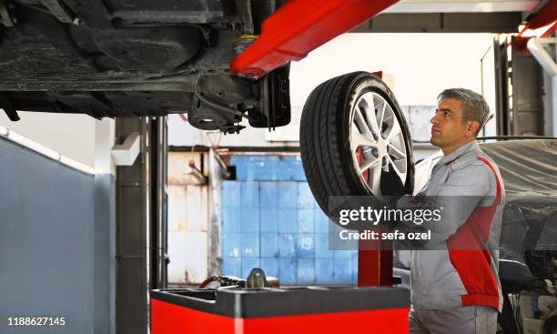 neumático de coche - extracción e instalación de piezas de vehículo sin necesidad de instalaren en el taller de reparación automática - instalador fotografías e imágenes de stock