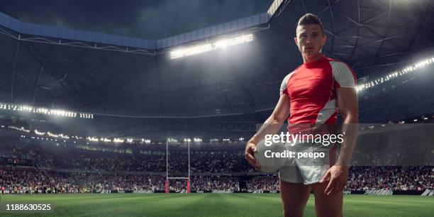 rugby-spieler steht mit ball im flutlicht-stadion vor spiel - rugbyball stock-fotos und bilder