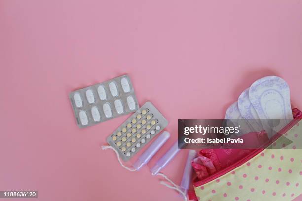 menstrual bag with cotton tampons, sanitary napkins and pills on pink background - menstruation stock pictures, royalty-free photos & images