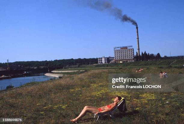 Une jeune femme bronze devant une centrale électrique à Poznan en juin 1983, Pologne.