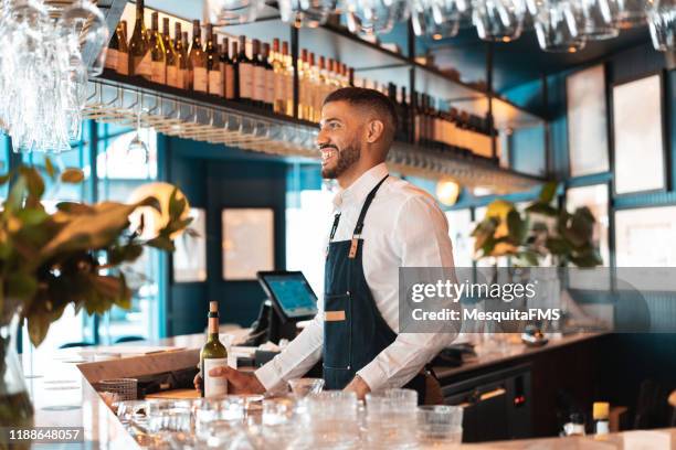 bartender holding a bottle of wine from the bar - food and drink establishment stock pictures, royalty-free photos & images