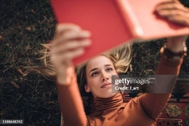 beautiful blonde woman reading book on a picnic. - reading female stock-fotos und bilder