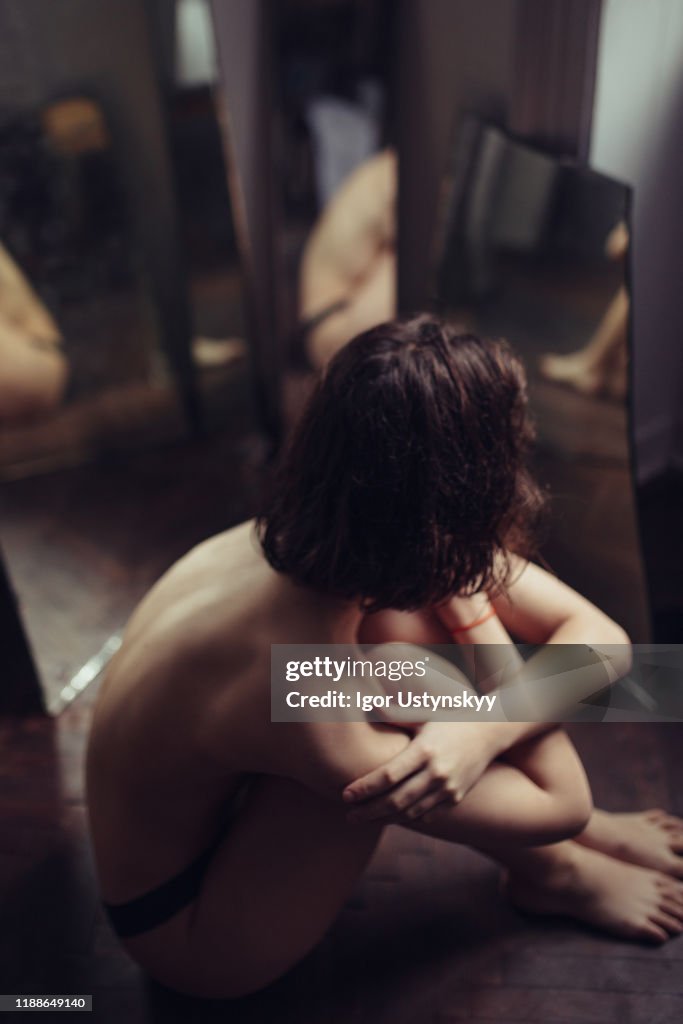 Young woman sitting between the mirrors