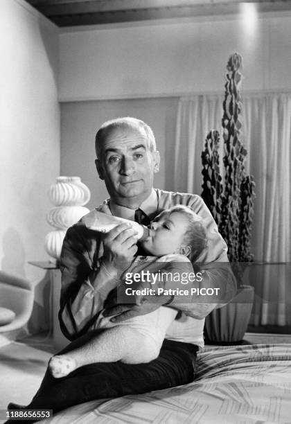 Louis de Funès donne le biberon à un bébé lors du tournage du film 'L'homme orchestre' réalisé par Serge Korber le 11 février 1970 Paris, France.
