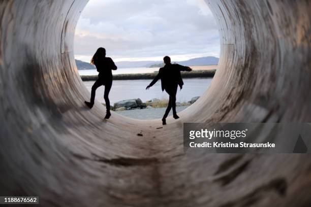 silhouettes of a boy and a girl in a tunnel - children playing silhouette stock pictures, royalty-free photos & images