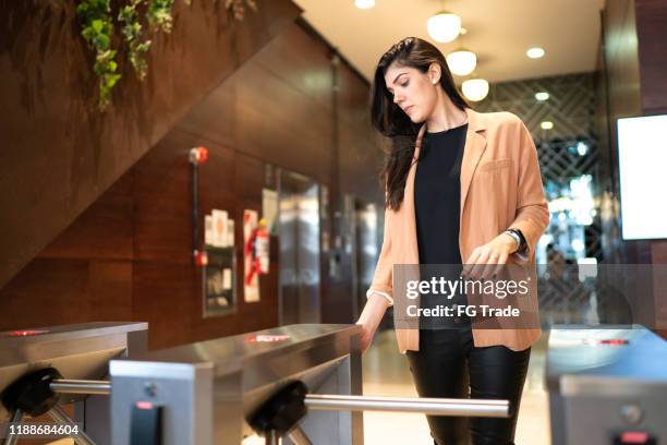 businesswoman passing by the turnstile - access control stock pictures, royalty-free photos & images