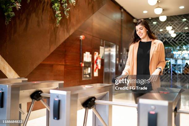 zakenvrouw die door het draaihek loopt - access stockfoto's en -beelden