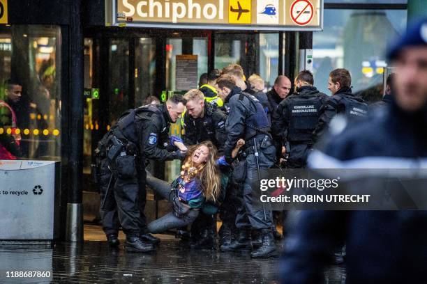 Royal Dutch police officers escort a Greenpeace activist during a protest to denounce airline pollution in the main hall of the Amsterdam Schiphol...