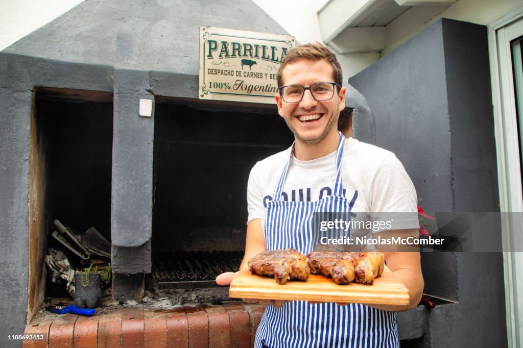 Millennial Argentinian cook presenting roasted rib eye and strip steaks