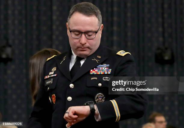Lt. Col. Alexander Vindman, National Security Council Director for European Affairs, checks his watch as he departs after testifying before the House...
