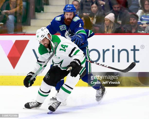 Jordie Benn of the Vancouver Canucks checks Jamie Benn of the Dallas Stars during their NHL game at Rogers Arena November 14, 2019 in Vancouver,...