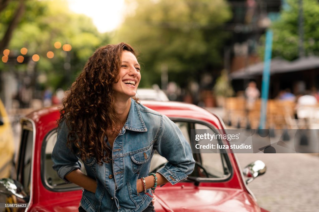 Woman leaning on the car hood on a road trip in Argentina