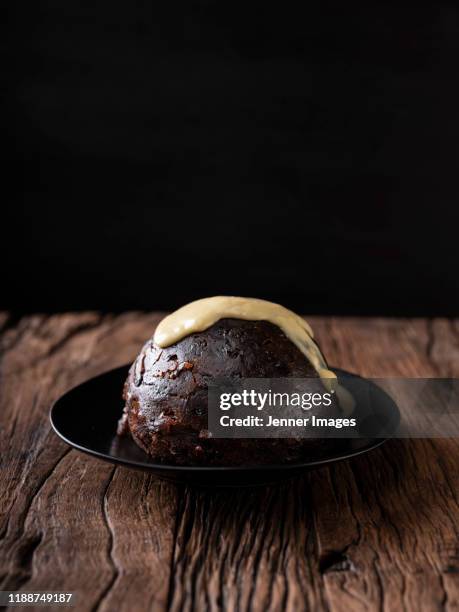 christmas pudding and custard on rustic wooden surface. - christmas pudding stock-fotos und bilder