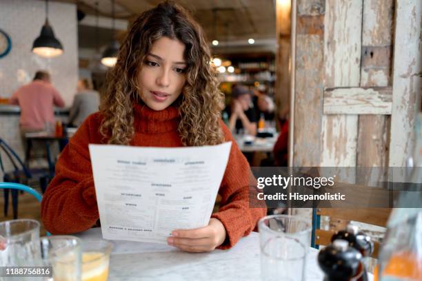 frau in einem restaurant lesen die speisekarte - menü stock-fotos und bilder