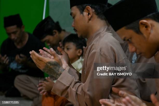 This picture taken on December 14, 2019 shows pencak silat practitioners, a martial art indigenous to Southeast Asia, praying ahead of a practice...