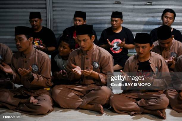 This picture taken on December 14, 2019 shows pencak silat practitioners, a martial art indigenous to Southeast Asia, praying ahead of a practice...