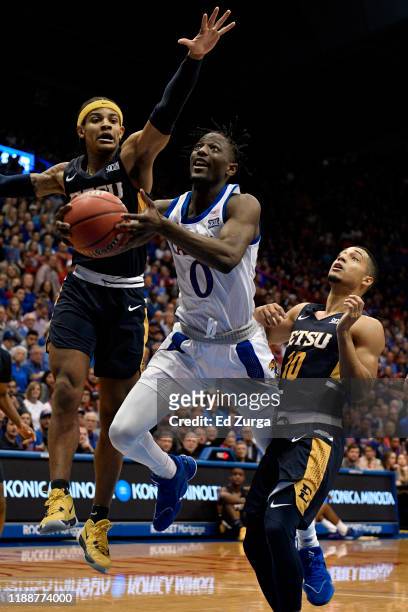 Marcus Garrett of the Kansas Jayhawks lays the ball up against Tray Boyd III and Patrick Good of the East Tennessee State Buccaneers of the East...