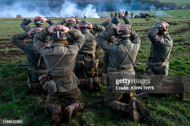 Actors wearing WWII US unifoms surrender to actors wearing WWII German uniforms during a historical re-enactment of the Battle of the Ardennes as...