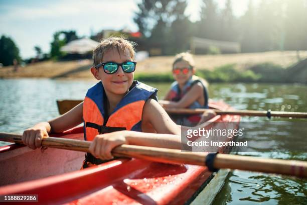 twee jongens genieten van kajakken op het meer - summer kayaking stockfoto's en -beelden