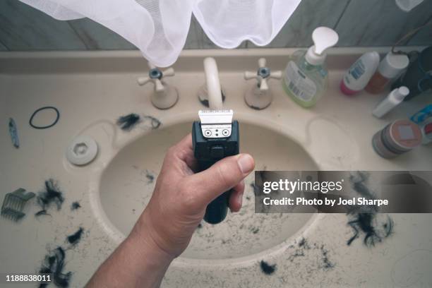 man holding electric shaver with hair all over sink - untidy sink stock-fotos und bilder