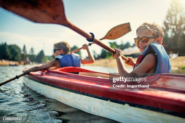 two boys enjoying kayaking on lake - family activity stock pictures, royalty-free photos & images