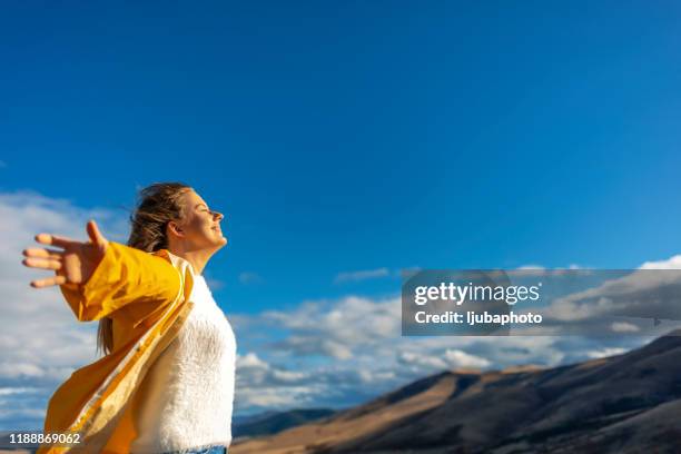 woman taking a breath in front of a spectacular view - breathe stock pictures, royalty-free photos & images