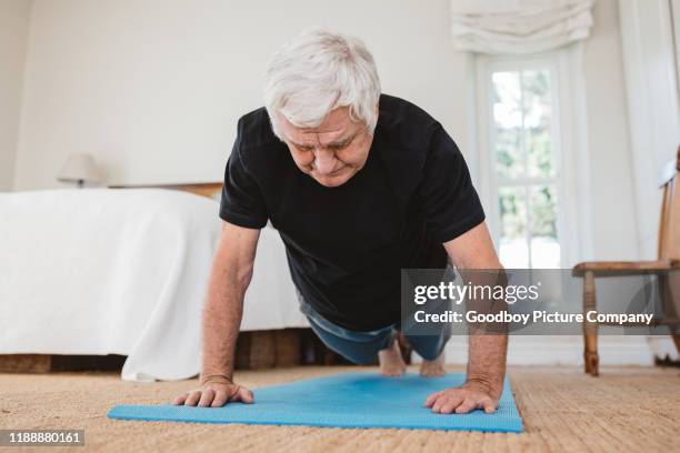 aktiver senior mann in einer planke pose beim yoga - senior yoga stock-fotos und bilder